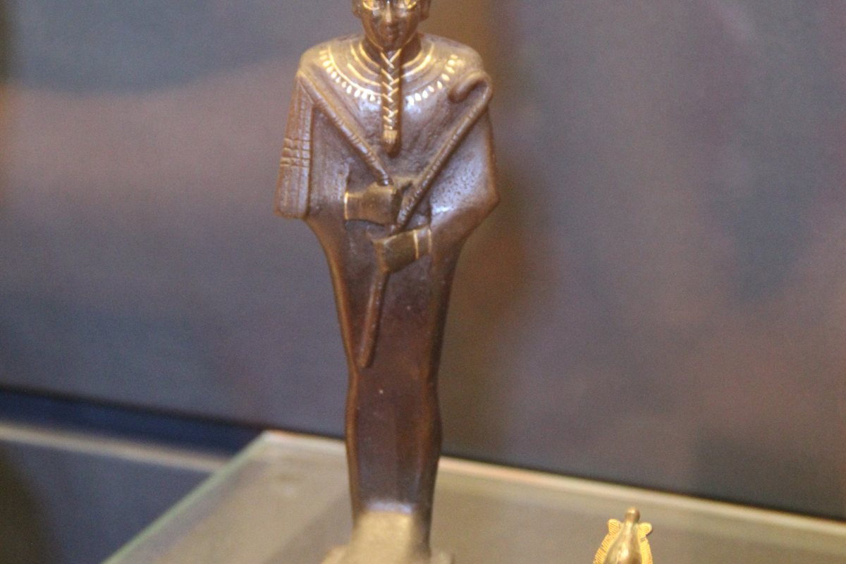 Group of ancient Egyptian bronze statues of Osiris in a museum case
